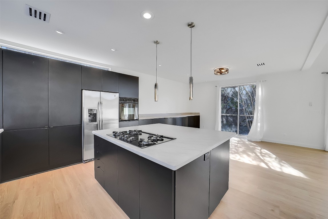 320 Detering Street Houston, TX 77007 - Photo 10 of 32 View from the kitchen facing the dining area, highlighting the extended wall-to-wall cabinetry that offers excellent storage. The island provides additional under-counter storage and a spacious work surface. Open layout allows for easy flow between the kitchen, dining, and living areas. Ideal for everyday meals and entertaining!