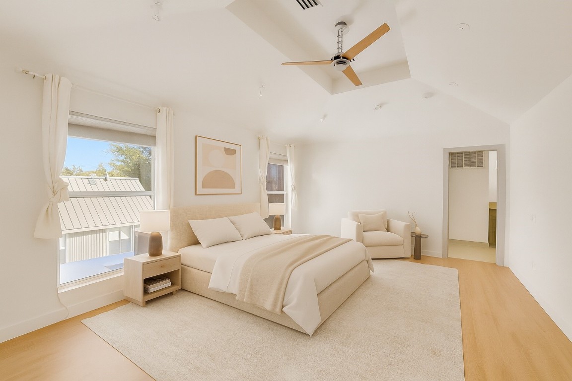 320 Detering Street Houston, TX 77007 - Photo 14 of 32 Primary bedroom, located on the third floor, features new hardwood floors (’25), ceiling fan, and two large front-facing windows that bring in great natural light. Spacious layout offers a quiet, private retreat separate from the main living areas. High ceiling and ceiling fan. Door leads to en suite bath. Note: photo has a been virtually staged.