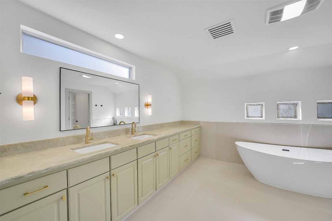 320 Detering Street Houston, TX 77007 - Photo 15 of 32 Recently updated primary bathroom features painted cabinetry and a new soaking tub! Windows bring in natural light while maintaining privacy. There is a separate tile shower, tile flooring, and a private water closet. Spacious walk-in closet completes this refreshed primary suite.