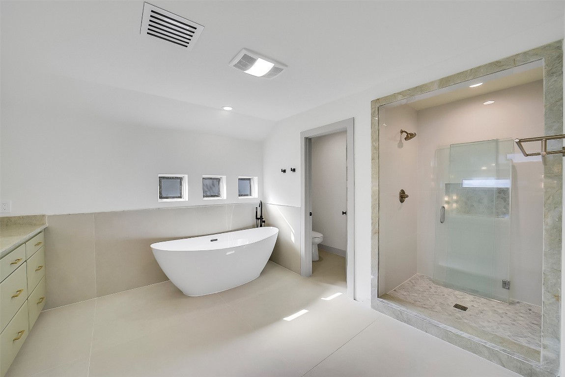 320 Detering Street Houston, TX 77007 - Photo 16 of 32 Another view of the updated primary bathroom showcasing the soaking tub, separate shower, and private water closet. Clean finishes, privacy windows, and updated cabinetry create a fresh, serene retreat.