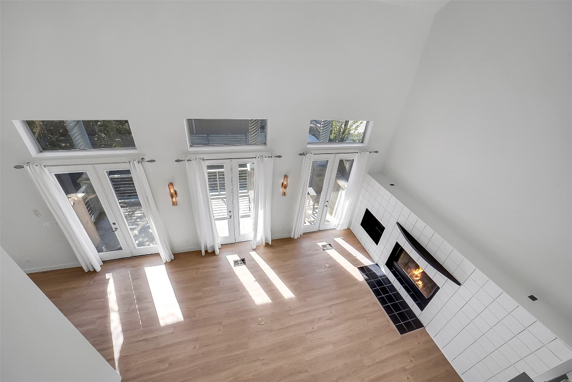 320 Detering Street Houston, TX 77007 - Photo 18 of 32 View from the third floor overlooking the living area, highlighting the impressive ceiling height and abundant natural light. Three sets of French doors open to the balcony, emphasizing the bright, open feel of the second-floor living space..