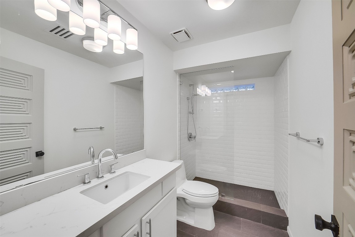 320 Detering Street Houston, TX 77007 - Photo 22 of 32 Secondary bathroom located on the first floor, features a walk-in shower w/ white subway tile walls, vanity with storage, and tile flooring. Updated plumbing & light fixtures and countertop. Conveniently positioned between the two secondary bedrooms for easy access. Clean, functional, and well-maintained.