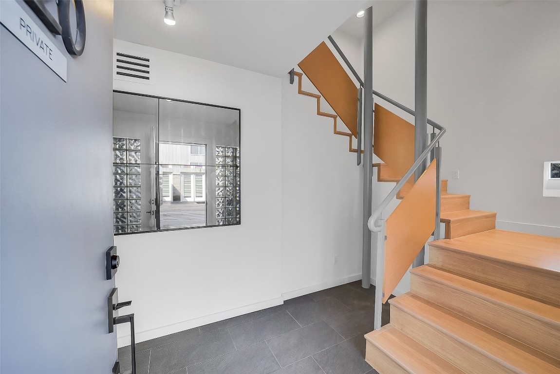 320 Detering Street Houston, TX 77007 - Photo 3 of 32 Entryway featuring wood staircase leading up to the second-floor main living area. Fresh interior paint, updated lighting, and new wood flooring in certain spaces (’25) set a clean, updated tone the moment you step inside. A functional layout with guest bedrooms & game room on the first floor, living on the second, primary suite on the third; offers comfortable everyday living.