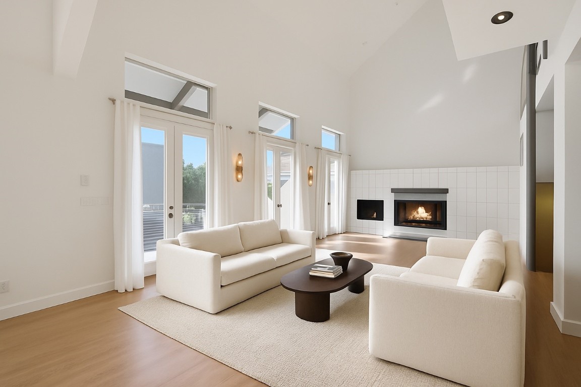 320 Detering Street Houston, TX 77007 - Photo 5 of 32 Second-floor living area featuring new wood flooring (’25), soaring 25’ ceiling height, and a cozy gas log fireplace with tile surround. Three sets of French doors open to the spacious covered balcony, bringing in tons of great natural light and creating an easy indoor/outdoor flow. Spacious layout ideal for everyday living and entertaining. Note: this photo has been virtually staged.