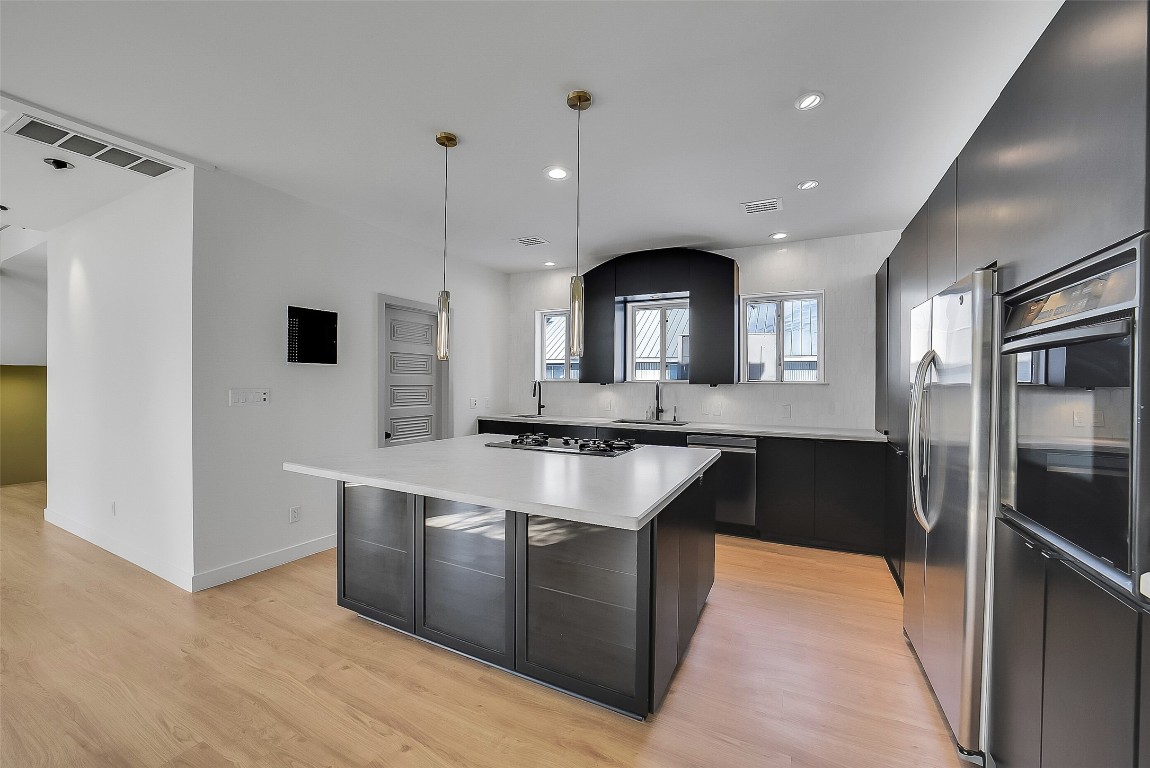 320 Detering Street Houston, TX 77007 - Photo 9 of 32 Another view of the kitchen showcasing the doorway the left leading to the utility room. Kitchen appliances that will remain with the lease include the refrigerator, oven, and dishwasher. Tons of cabinetry, new countertops (’25), and new wood flooring (’25) create a clean, updated look throughout the space.