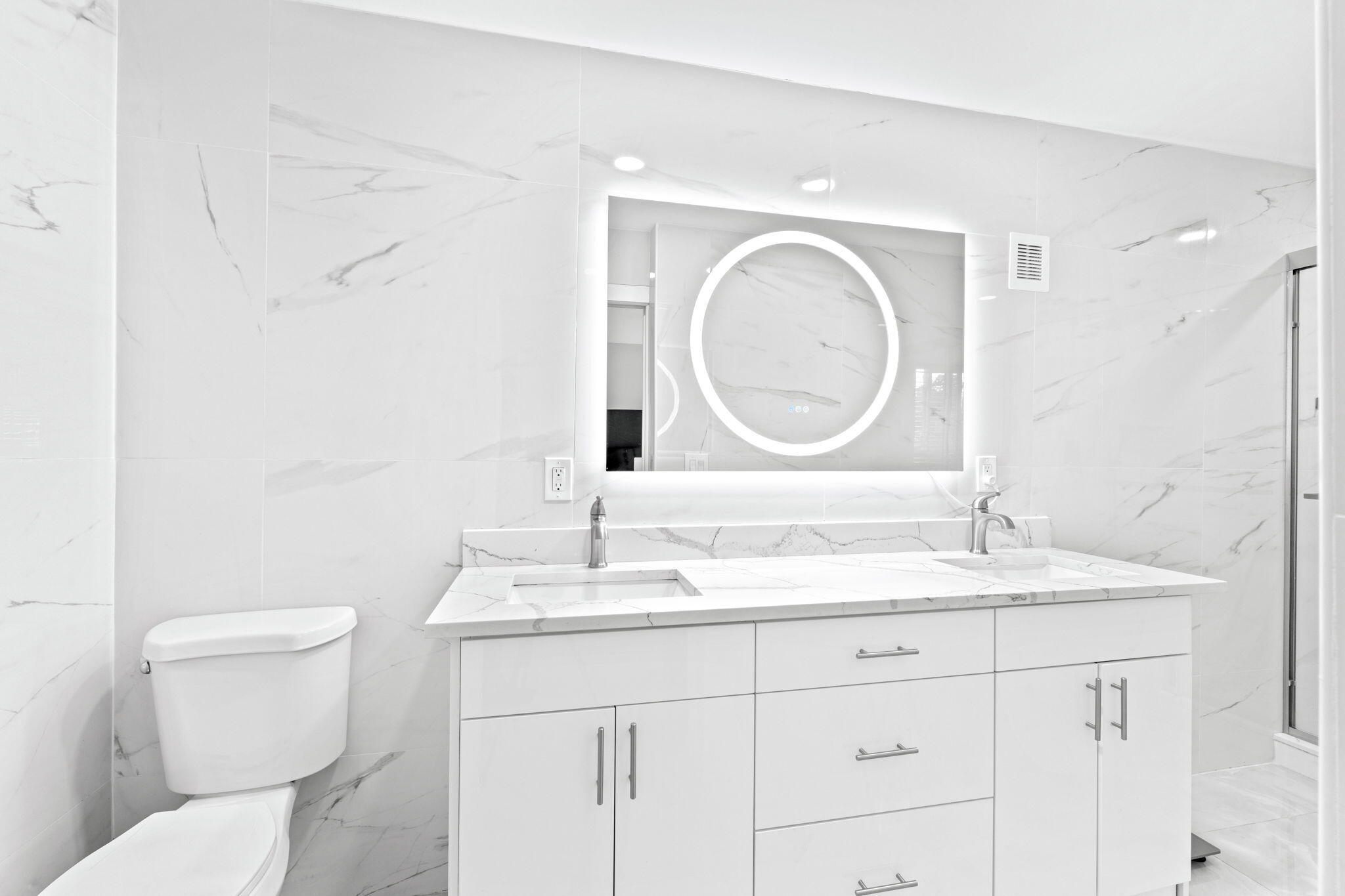 12293 Old Country Road South Wellington, FL 33414 - Photo 15 of 32 a bathroom with a toilet a double vanity sink and a mirror