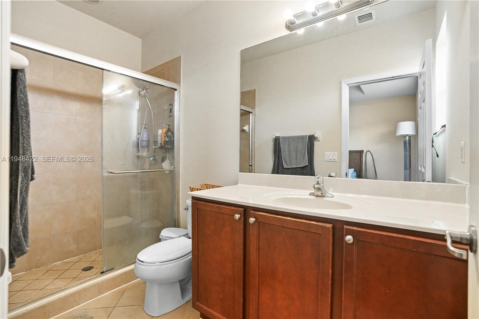 9105 Southwest 227th Street, Unit 9 Cutler Bay, FL 33190 - Photo 14 of 37 a bathroom with a granite countertop sink toilet mirror and shower