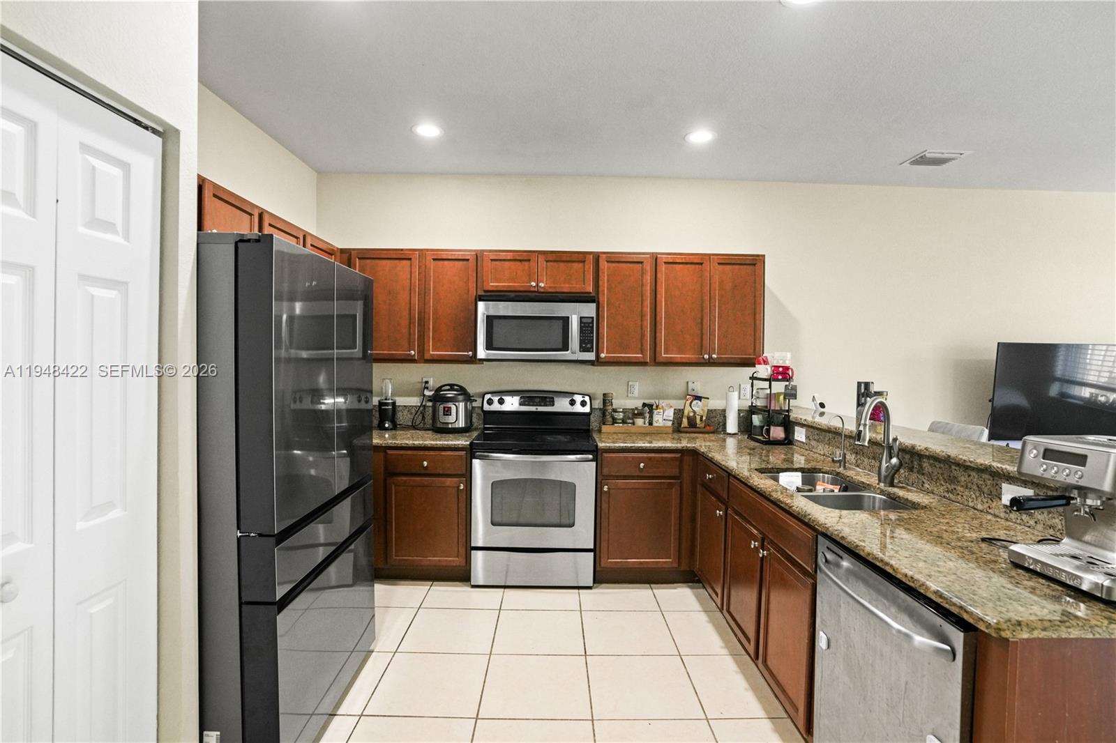 9105 Southwest 227th Street, Unit 9 Cutler Bay, FL 33190 - Photo 6 of 37 a kitchen with stainless steel appliances granite countertop wooden cabinets a stove a sink and a refrigerator