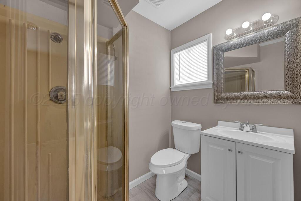 312 Southwest 45th Avenue Amarillo, TX 79110 - Photo 17 of 23 a bathroom with a toilet a sink a mirror a window and vanity