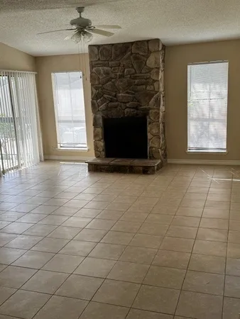 an empty room with windows and fireplace