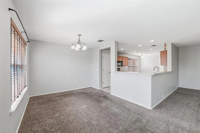 an empty room with kitchen view and wooden floor