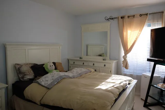 a bedroom with bed and a flat tv screen on a dresser