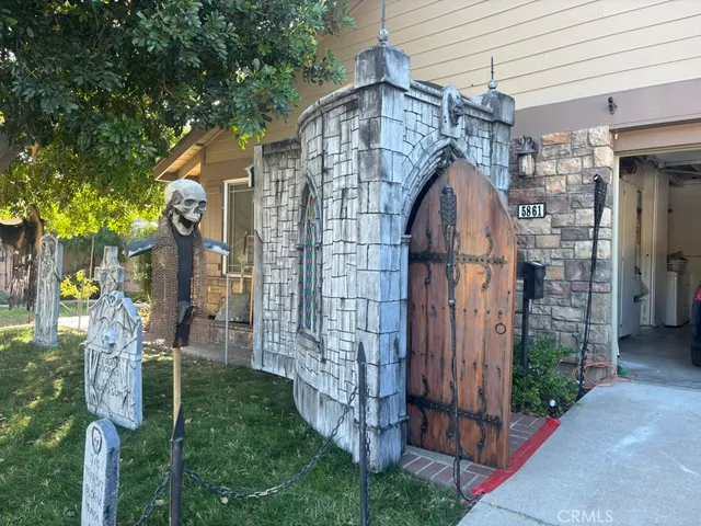 a view of yellow house with a yard and large tree