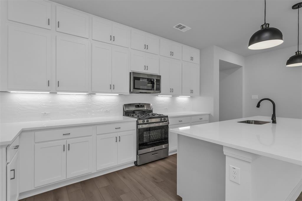 1031 Rylan Street Midlothian, TX 76065 - Photo 6 of 28 Modern kitchen featuring white shaker cabinetry, stainless steel appliances, a gas range, white countertops, and wood-finish flooring