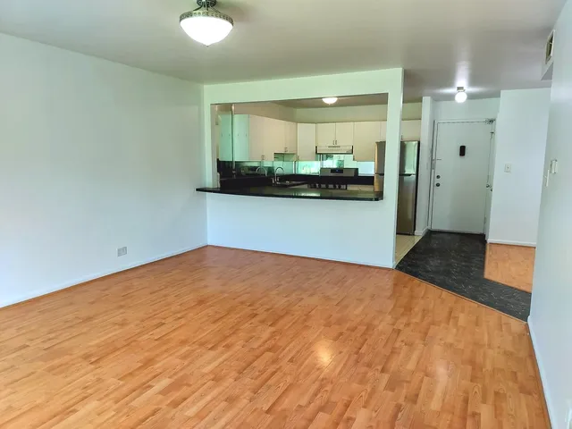 a view of a room with wooden floor and kitchen view