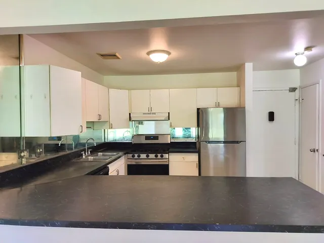 a kitchen with kitchen island granite countertop a sink a counter and stainless steel appliances