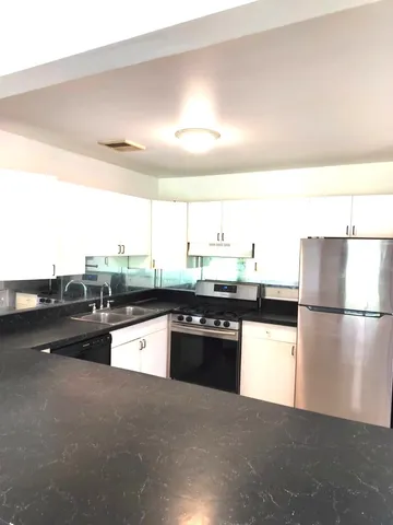 a kitchen with stainless steel appliances granite countertop a stove a sink and a refrigerator