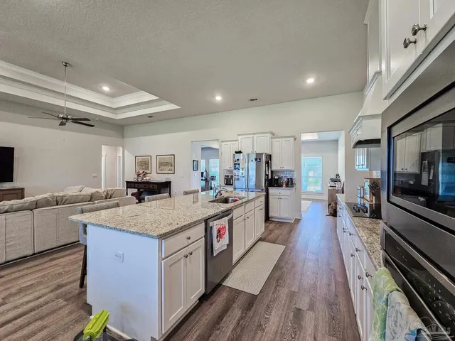 a large kitchen with stainless steel appliances granite countertop plenty wooden cabinets counter space and wooden floor
