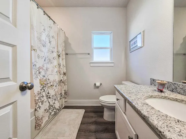 a bathroom with a granite countertop sink toilet and shower