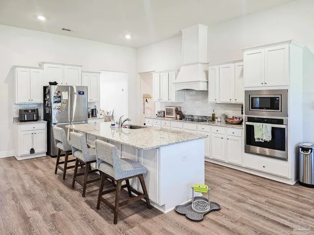 a kitchen with stainless steel appliances kitchen island granite countertop a table chairs refrigerator and microwave