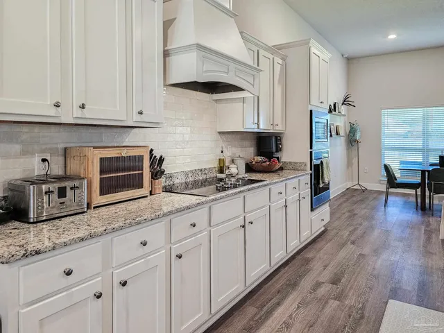 a kitchen with granite countertop a sink a stove and cabinets