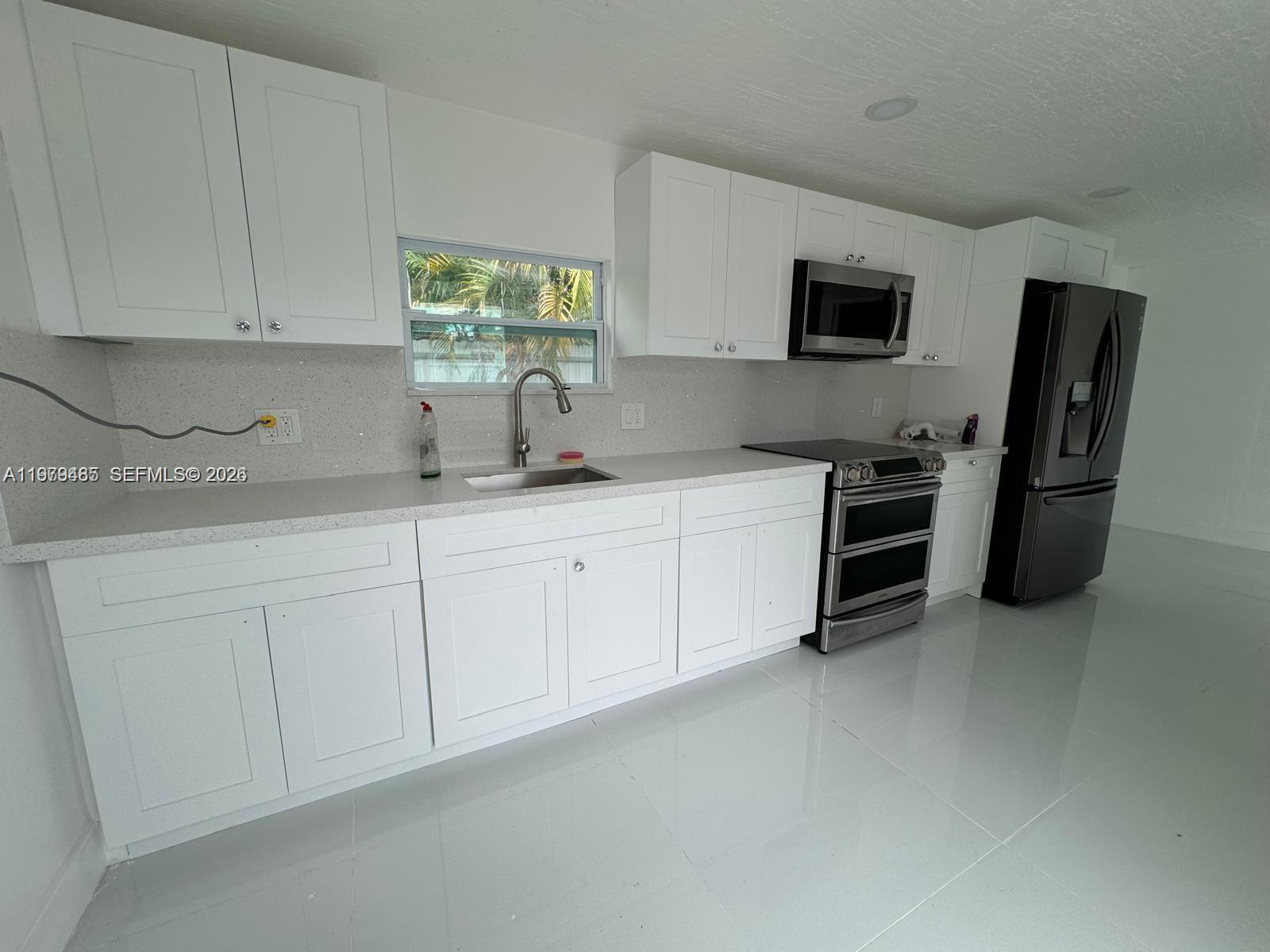 3340 Southwest 94th Place, Unit 1 Miami, FL 33165 - Photo 6 of 21 a kitchen with stainless steel appliances granite countertop a sink dishwasher a refrigerator and a microwave