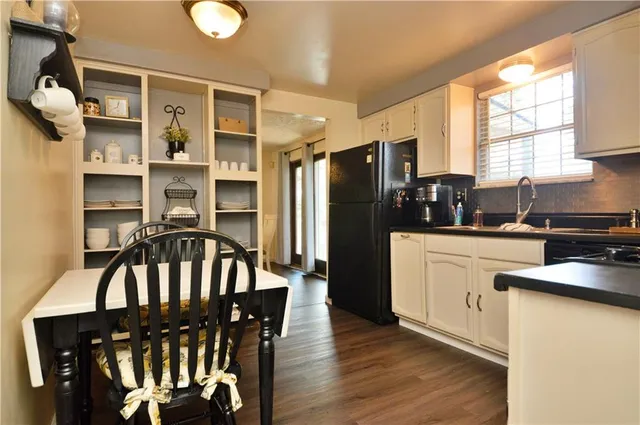 a kitchen with stainless steel appliances granite countertop a refrigerator a stove a sink dishwasher and white cabinets with wooden floor