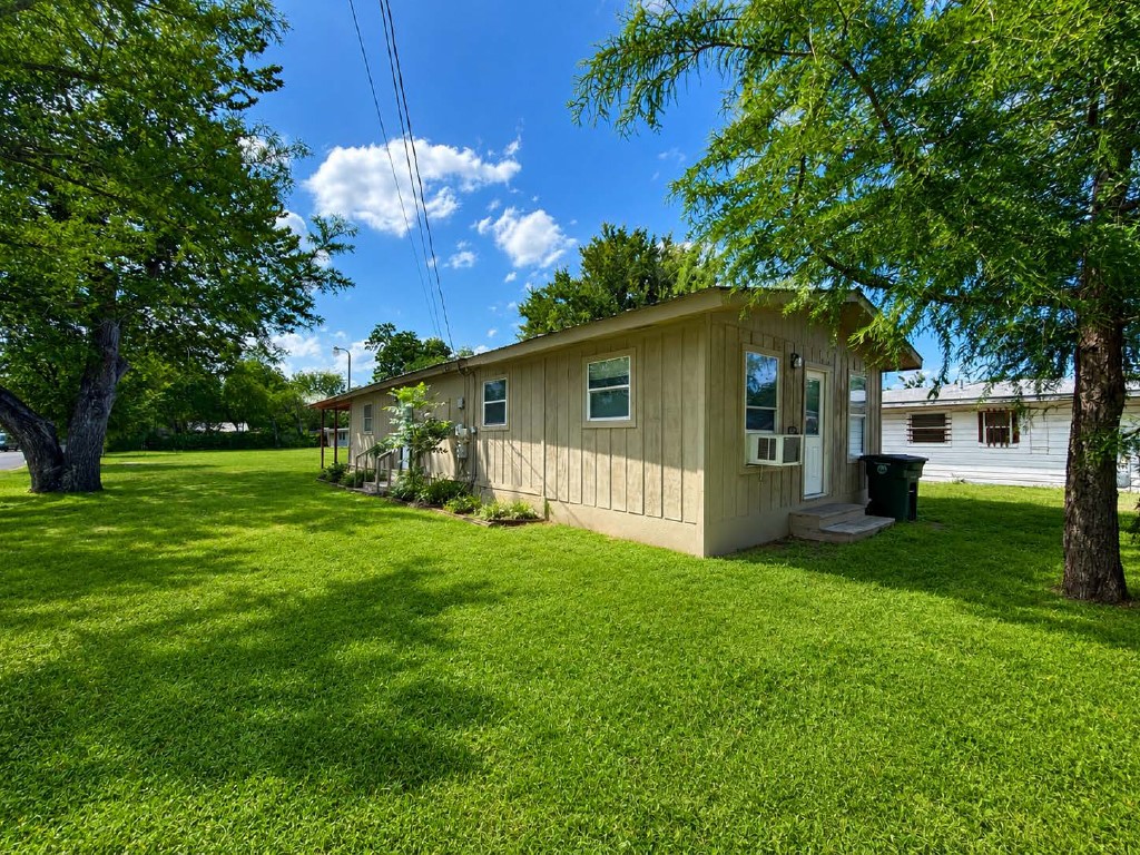 610 Gunter Street Austin, TX 78702 - Photo 3 of 16 A modest home on a well-kept, lush green yard, framed by mature trees.