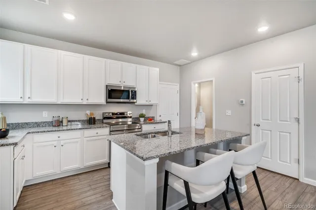 a kitchen with granite countertop white cabinets and stainless steel appliances