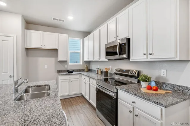 a kitchen with granite countertop white cabinets sink and stainless steel appliances