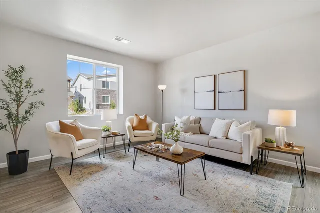 a living room with furniture a lamp paintings and a window