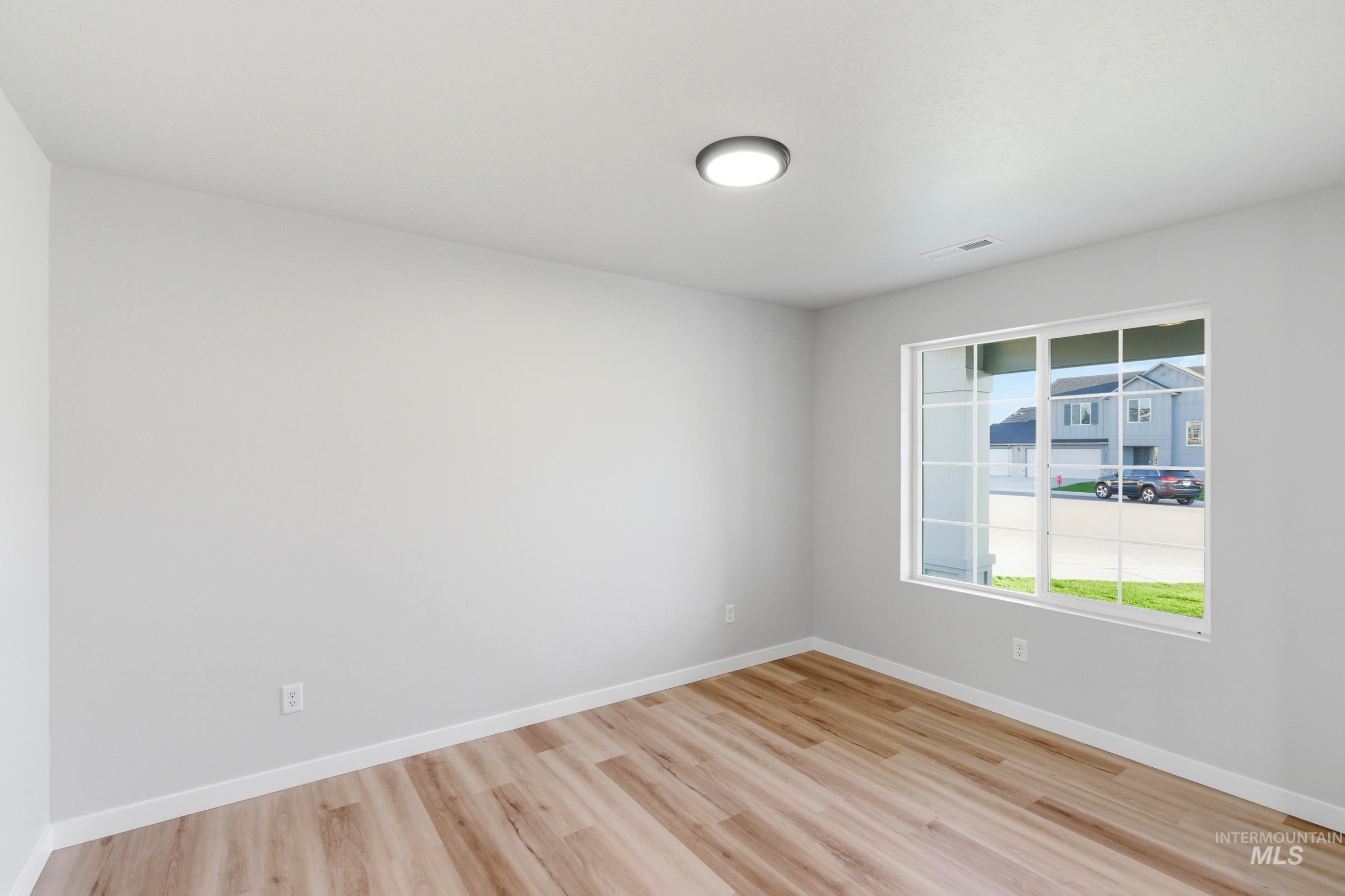 13709 Redway Court Caldwell, ID 83607 - Photo 11 of 28 Spacious room featuring wood-finish flooring, light gray walls, and a large window with white muntins
