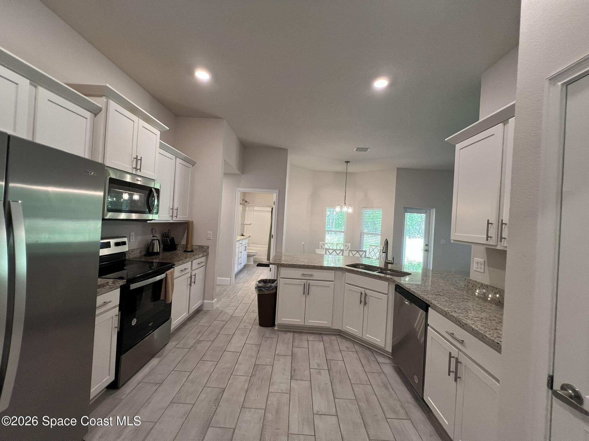 8752 Waterstone Boulevard Fort Pierce, FL 34951 - Photo 6 of 24 a large kitchen with stainless steel appliances granite countertop a stove top oven a sink and dishwasher