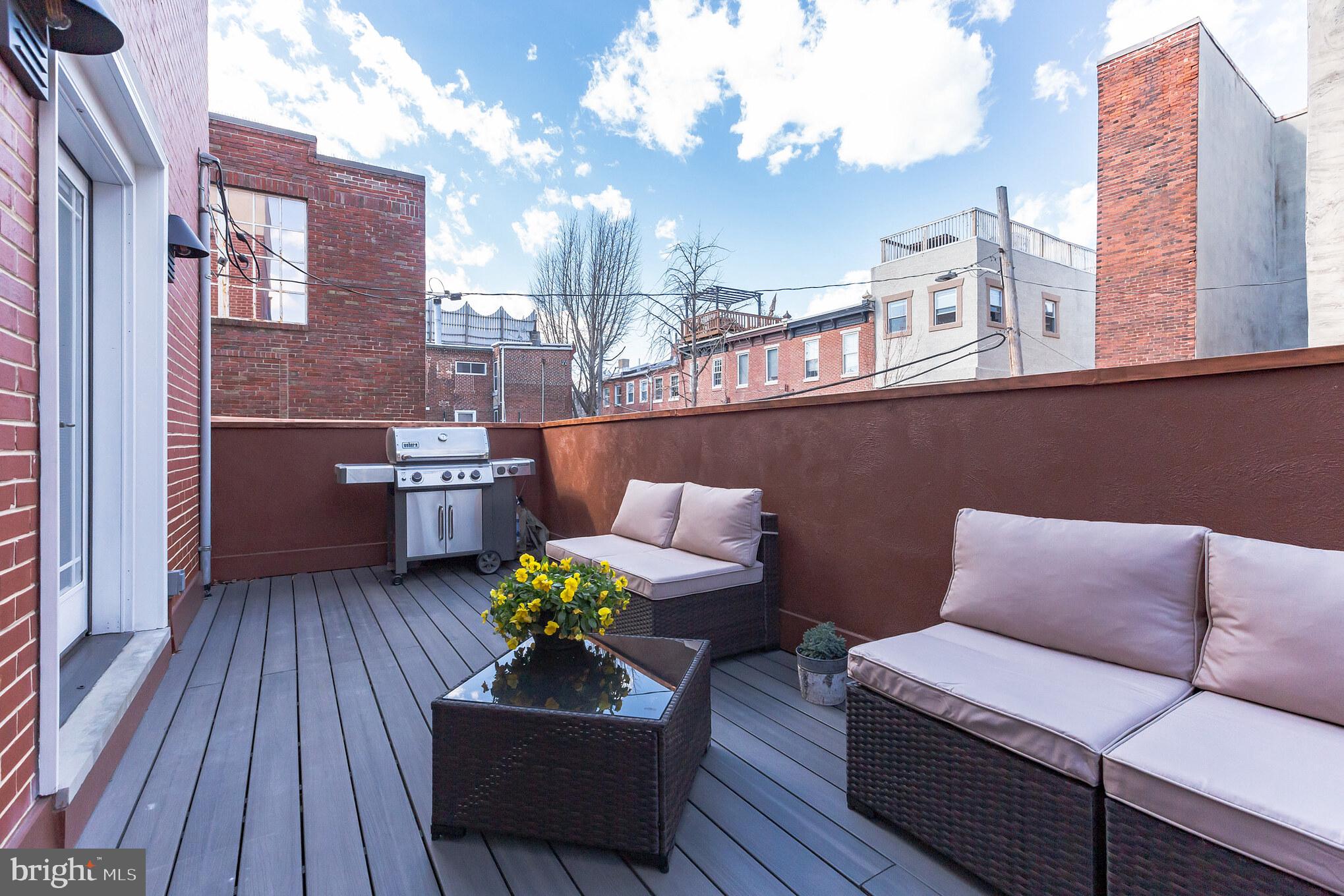 a view of a rooftop deck with couch and chairs