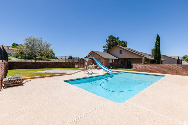 1470 Redwood Tree Street St. George, UT 84790 - Photo 47 of 53 Expansive concrete patio surrounding a rectangular swimming pool with a blue slide