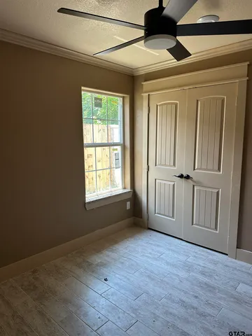 a view of empty room with wooden floor and fan