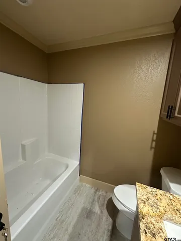 a white toilet sitting next to a bath tub