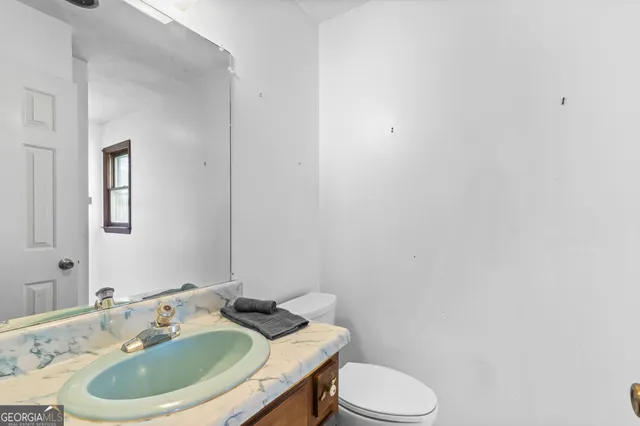 a view of a backyard with plants and white chairs