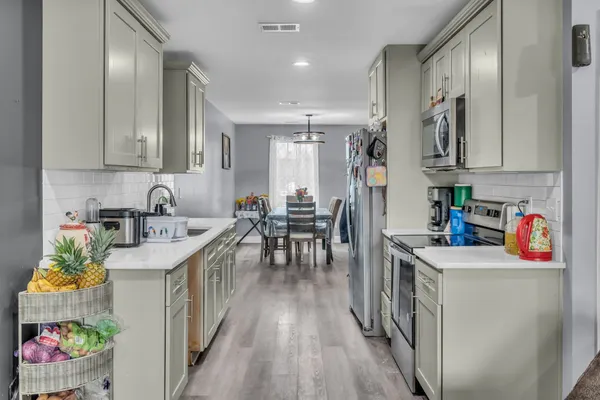 a kitchen that has a lot of cabinets in it and wooden floors