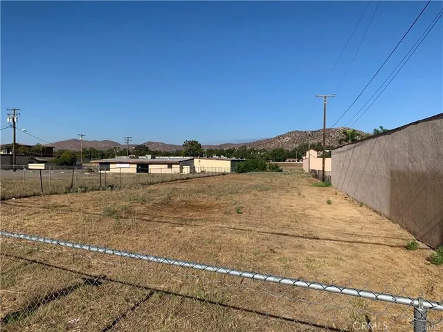 a view of a dry yard with wooden fence
