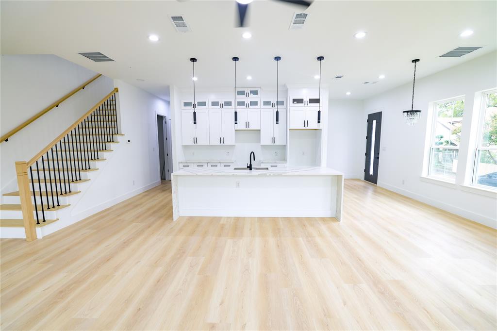 a large white kitchen with a large window a sink stainless steel appliances and cabinets