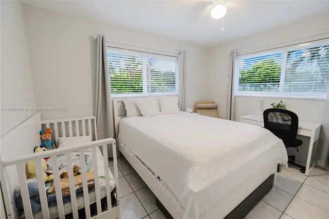 a bedroom with a bed next to a window with wooden floor