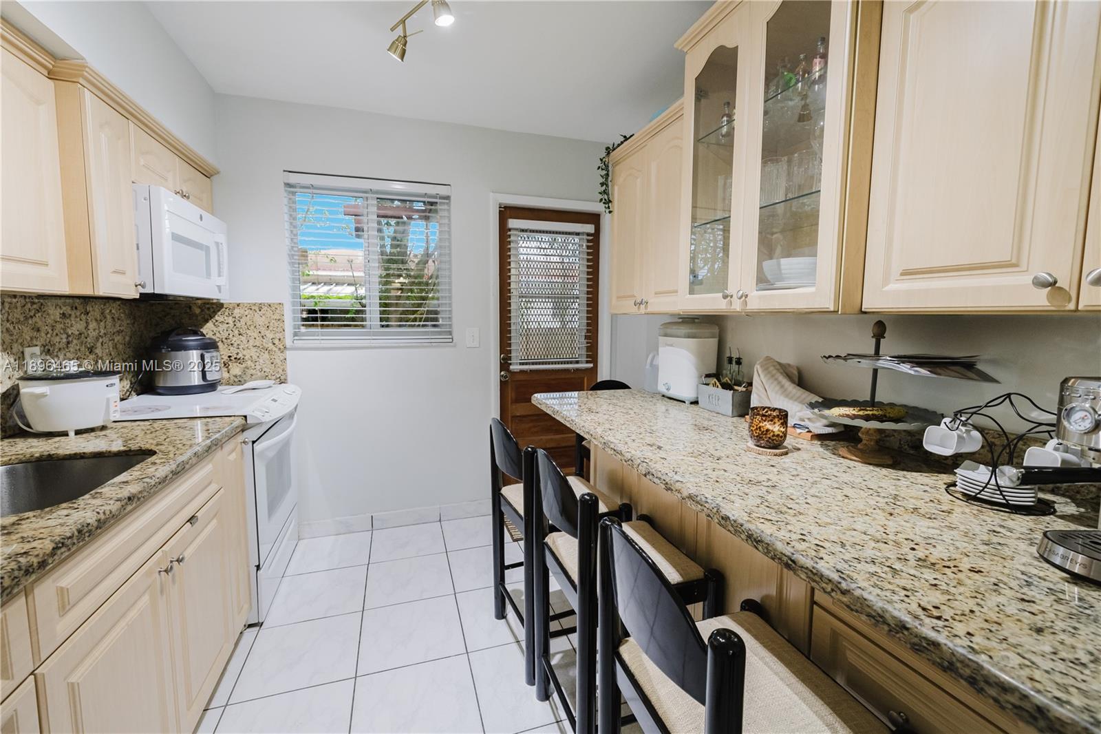 2211 Southwest 75th Avenue, Unit 1 Miami, FL 33155 - Photo 7 of 9 a kitchen with granite countertop a sink a stove and cabinets