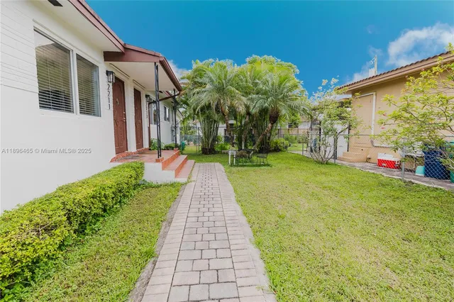 a front view of a house with a yard and potted plants