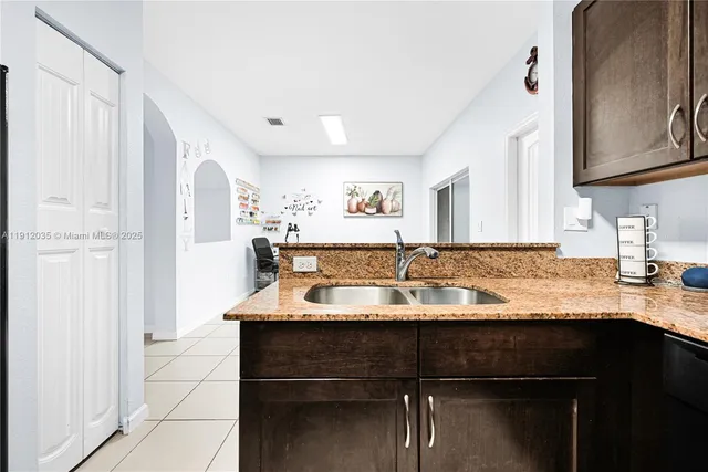 a kitchen with kitchen island granite countertop a sink cabinets and wooden floor