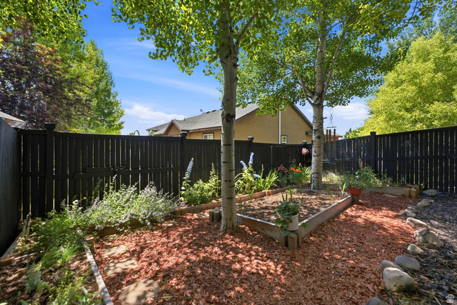 5196 Rodeo Circle Oakley, UT 84055 - Photo 53 of 57 Fenced yard featuring a wooden privacy fence, mature trees, wood-edged garden beds, and ground cover