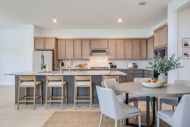 a kitchen with appliances a table and chairs in it