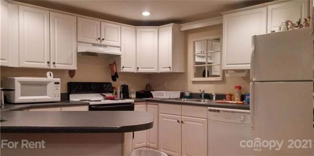 a kitchen with kitchen island a sink a stove and white cabinets