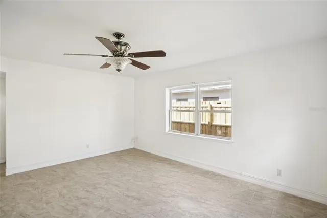 an empty room with a window and a ceiling fan