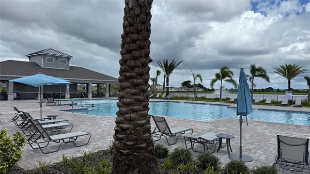 a view of a swimming pool with lawn chairs under an umbrella